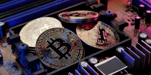 Golden coins with bitcoin symbol on electronic circuits in a computer mainboard.